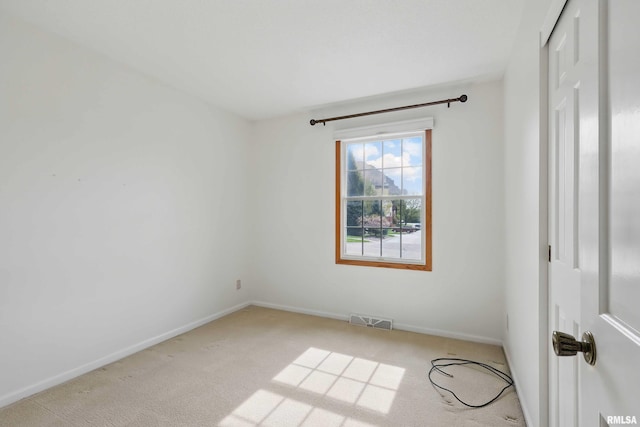carpeted spare room featuring visible vents and baseboards