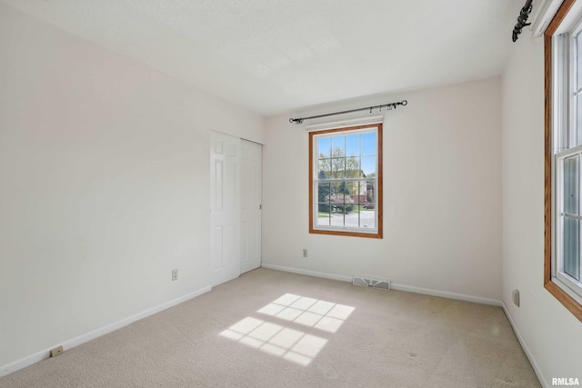 unfurnished room with visible vents, carpet flooring, and baseboards