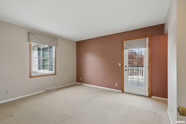 carpeted spare room featuring visible vents and baseboards