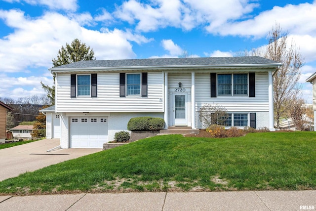 raised ranch with brick siding, a garage, a front lawn, and driveway