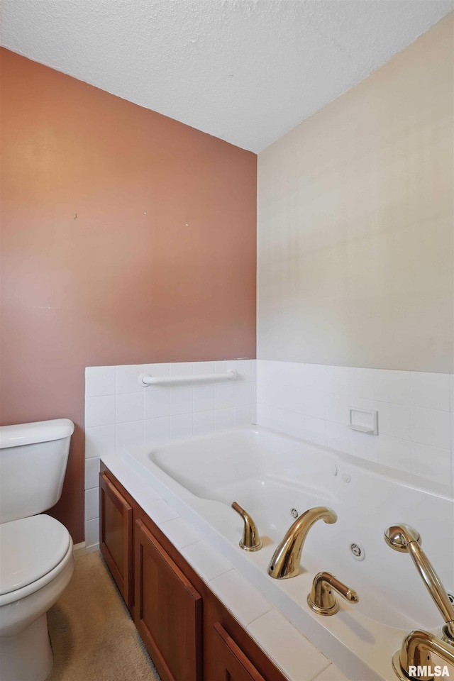full bathroom with a tub with jets, a textured ceiling, and toilet