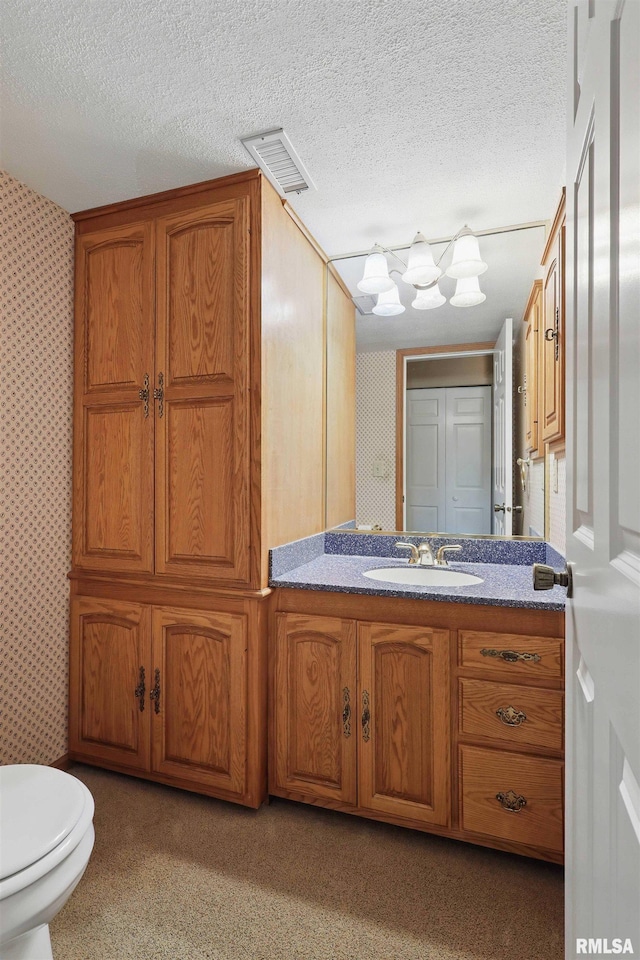 bathroom featuring toilet, wallpapered walls, visible vents, and vanity