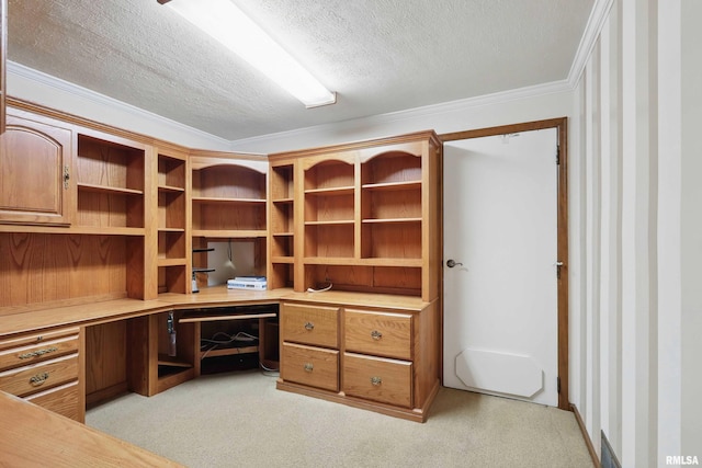 unfurnished office featuring a textured ceiling, light colored carpet, ornamental molding, and built in study area