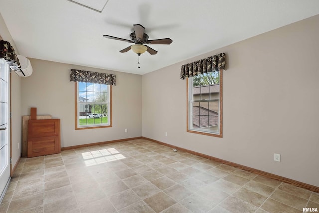 empty room with an AC wall unit, a ceiling fan, and baseboards