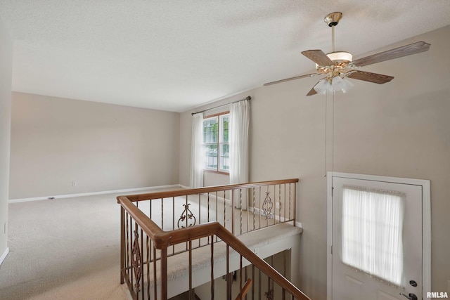 interior space featuring a ceiling fan, baseboards, carpet, and a textured ceiling