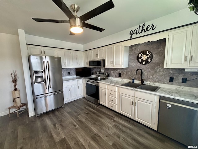 kitchen with appliances with stainless steel finishes, a sink, a ceiling fan, white cabinetry, and tasteful backsplash