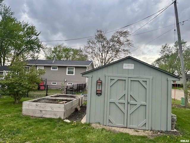 view of shed featuring fence and a vegetable garden