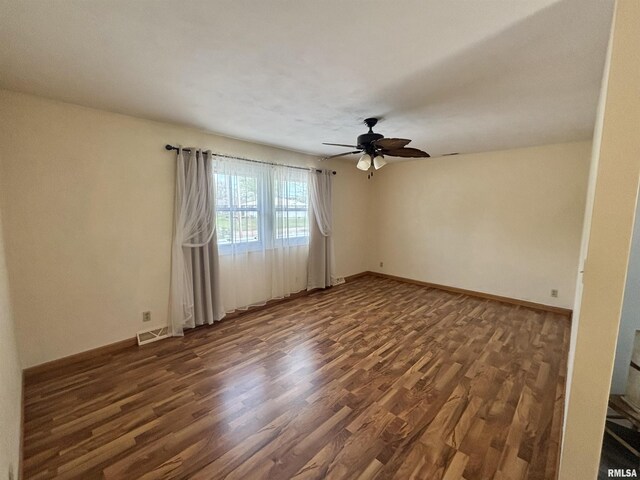 unfurnished room with visible vents, dark wood-style flooring, ceiling fan, and baseboards