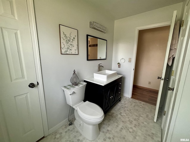 half bathroom with toilet, baseboards, and vanity
