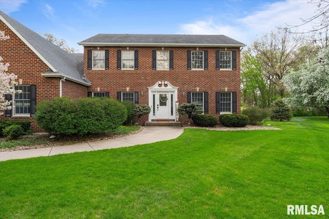 colonial home with brick siding and a front yard