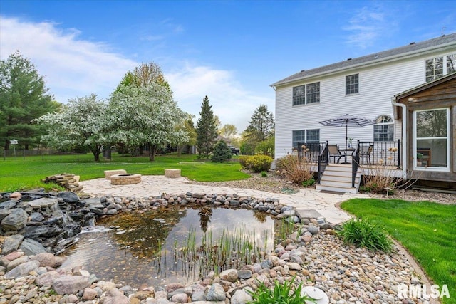 view of yard featuring a small pond, a deck, and an outdoor fire pit