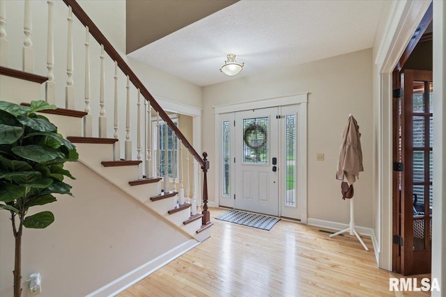 entryway with baseboards, hardwood / wood-style flooring, and stairway