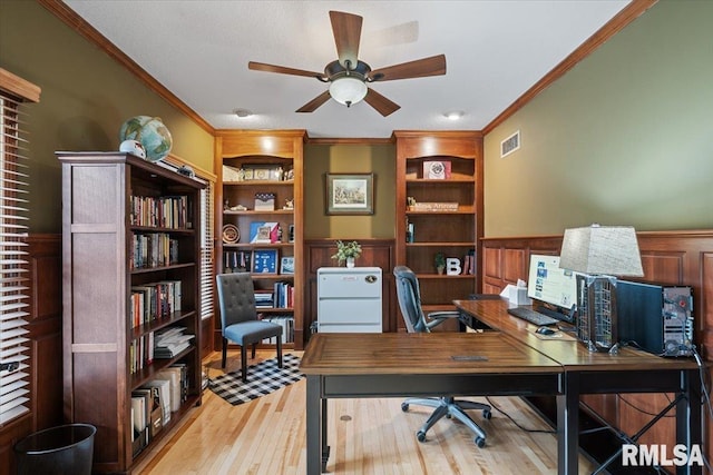 office with wainscoting, ceiling fan, visible vents, and ornamental molding