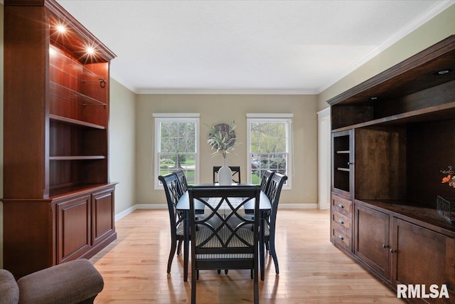 dining space with baseboards, ornamental molding, and light wood-type flooring