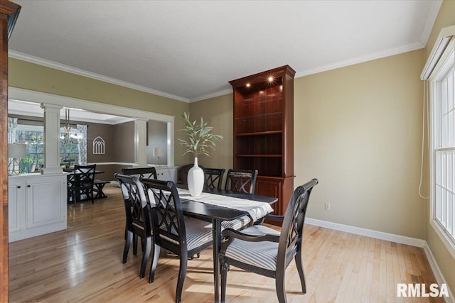 dining area featuring crown molding, a chandelier, baseboards, light wood-type flooring, and ornate columns