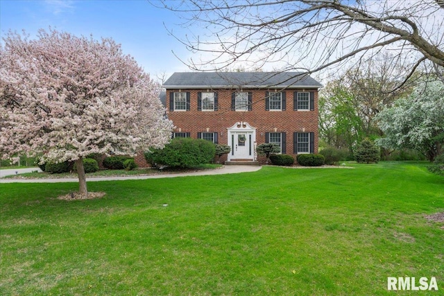 colonial house featuring a front yard and brick siding