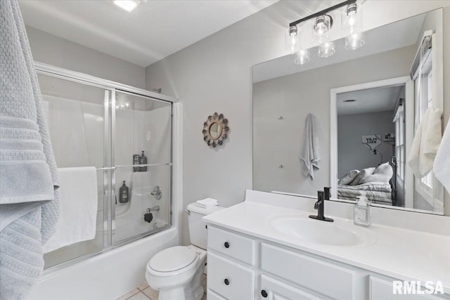 bathroom with vanity, tile patterned floors, toilet, and shower / bath combination with glass door