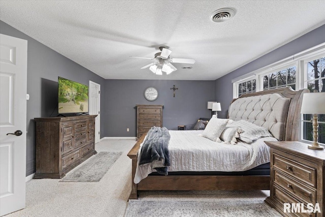 carpeted bedroom featuring baseboards, ceiling fan, a textured ceiling, and visible vents