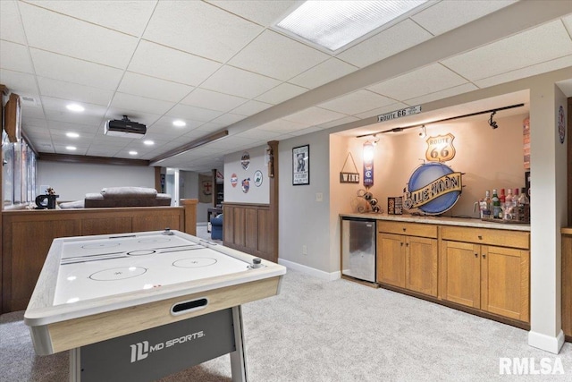 playroom featuring light colored carpet, a dry bar, baseboards, beverage cooler, and a drop ceiling