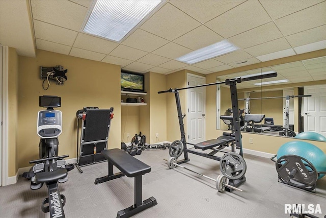 workout area featuring baseboards and a drop ceiling