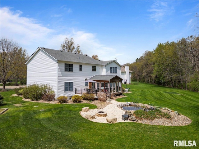 rear view of house featuring a lawn, a wooden deck, a patio area, and an outdoor fire pit
