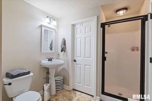 bathroom with baseboards, toilet, and a shower stall
