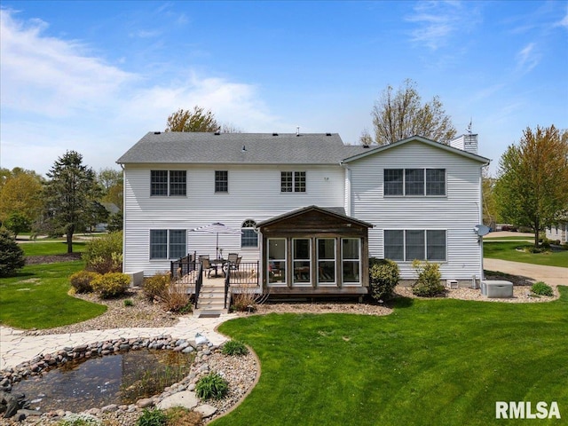 rear view of property with a yard, a deck, and a chimney