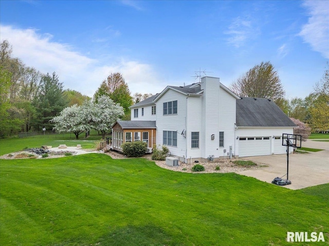 rear view of house featuring concrete driveway, a lawn, and an attached garage