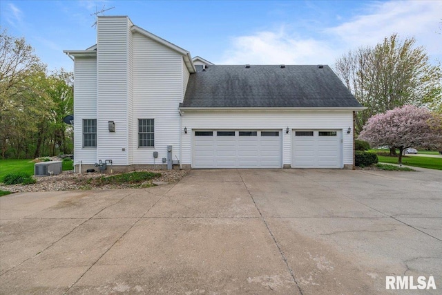 view of property exterior with a shingled roof, an attached garage, a chimney, cooling unit, and driveway