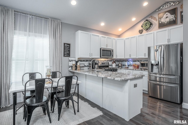 kitchen featuring decorative backsplash, a peninsula, lofted ceiling, recessed lighting, and stainless steel appliances