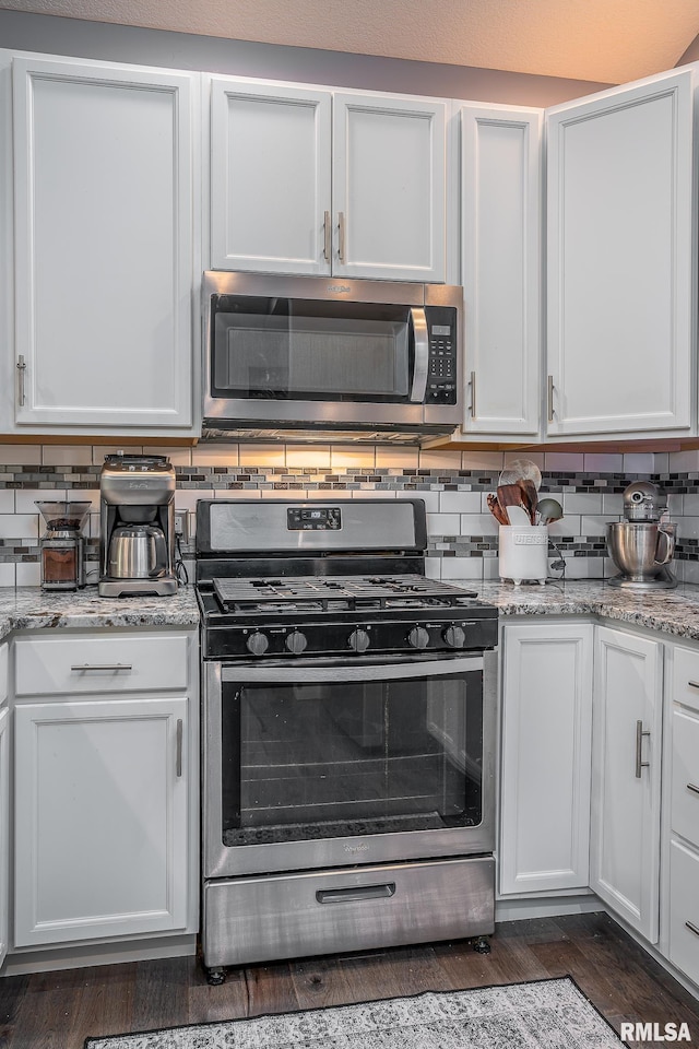 kitchen featuring backsplash, dark wood-style flooring, white cabinets, and appliances with stainless steel finishes