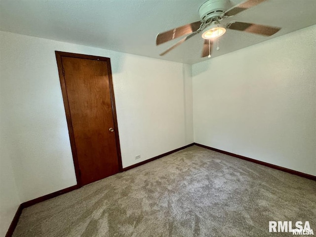carpeted spare room with ceiling fan and baseboards