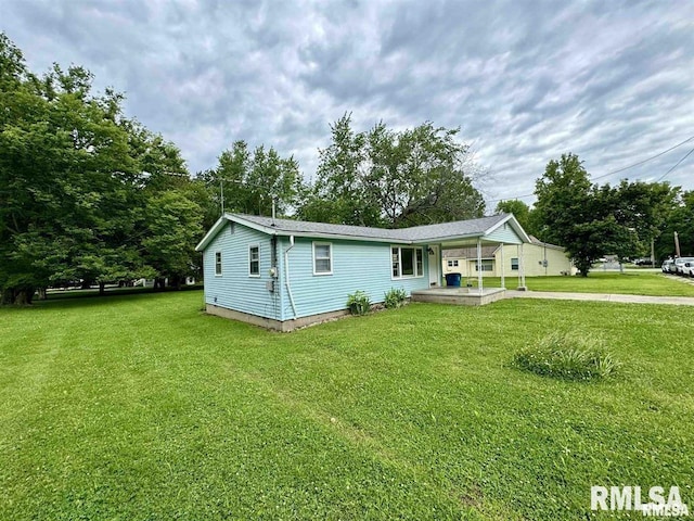 view of front of property featuring an attached carport, a front lawn, and concrete driveway