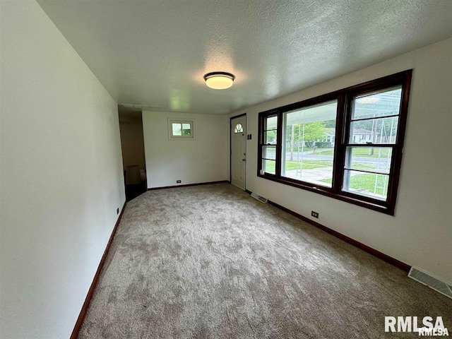 empty room featuring carpet flooring, a textured ceiling, and baseboards