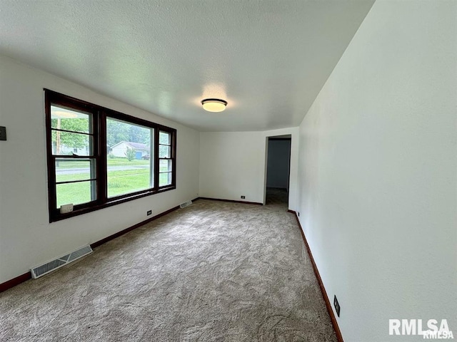 carpeted empty room with baseboards and a textured ceiling