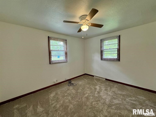 carpeted empty room featuring plenty of natural light, ceiling fan, a textured ceiling, and baseboards