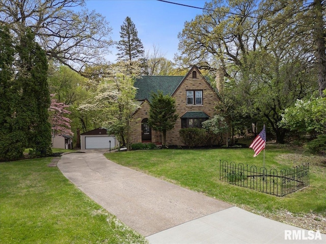 tudor-style house with an outbuilding, a garage, brick siding, fence, and a front lawn