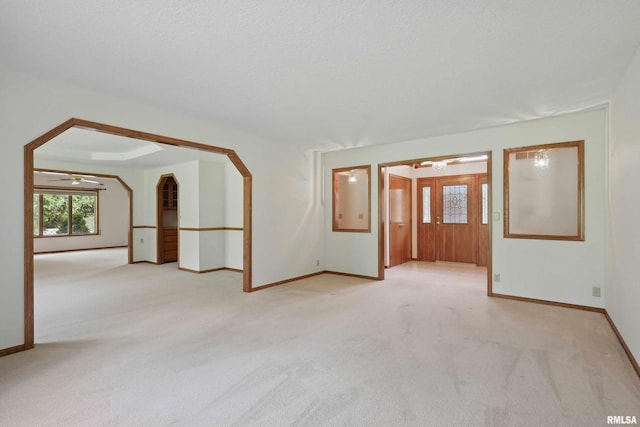 unfurnished room with light colored carpet, a ceiling fan, and baseboards