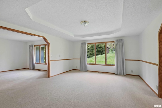 carpeted empty room with a raised ceiling, baseboards, a textured ceiling, and visible vents