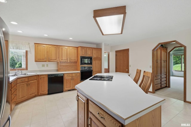 kitchen with a kitchen island, a sink, a healthy amount of sunlight, and black appliances