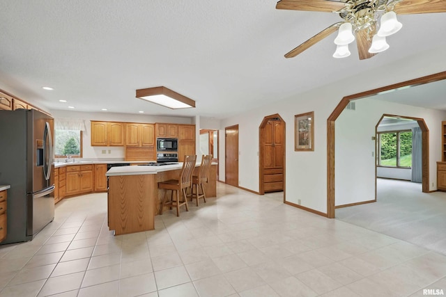 kitchen with stainless steel refrigerator with ice dispenser, light countertops, plenty of natural light, and black microwave