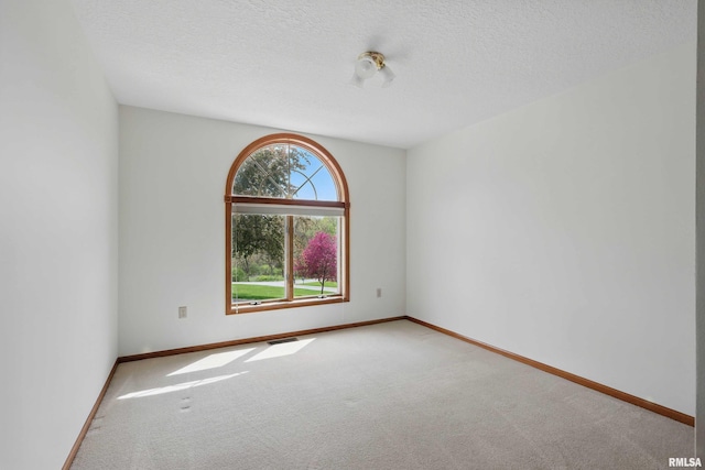 carpeted spare room with baseboards, a textured ceiling, and visible vents