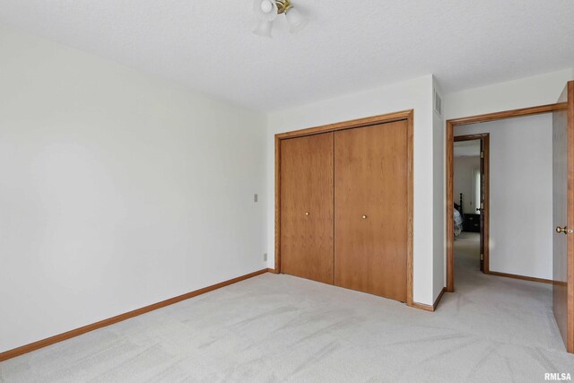 unfurnished bedroom with light colored carpet, baseboards, and a closet