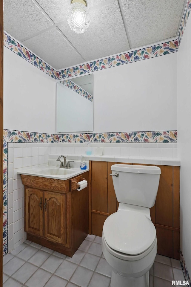 bathroom featuring toilet, tile walls, a wainscoted wall, and vanity