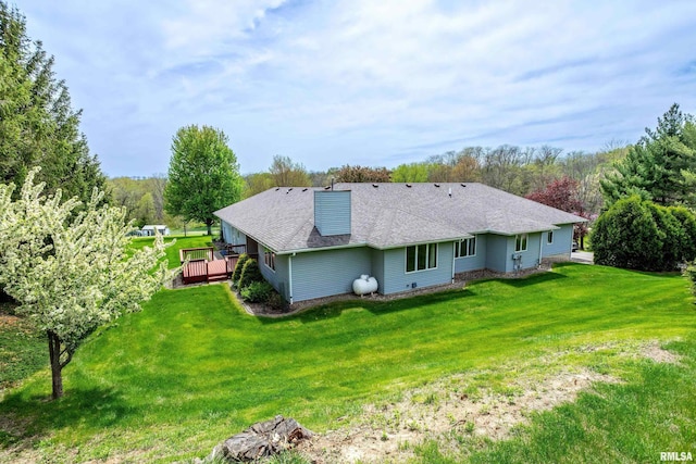 rear view of property with a lawn, a chimney, a shingled roof, and a deck