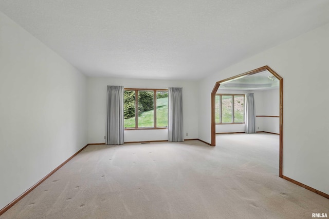 carpeted spare room featuring baseboards, arched walkways, and visible vents