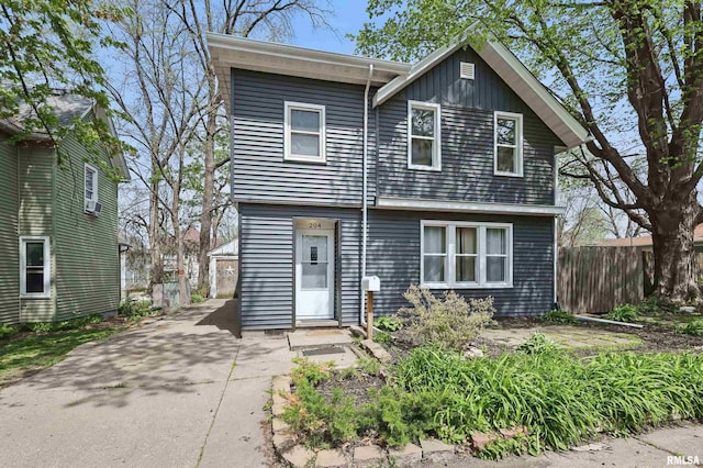colonial-style house featuring fence, a detached garage, and board and batten siding