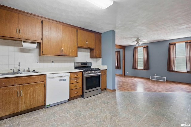 kitchen with brown cabinets, a sink, stainless steel gas range oven, dishwasher, and visible vents