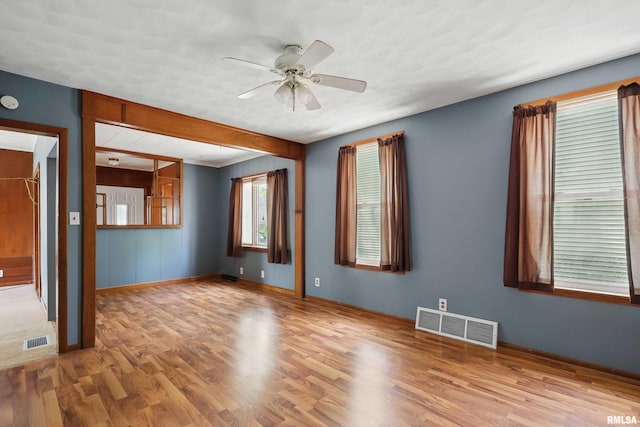 unfurnished room with visible vents, a ceiling fan, baseboards, and wood finished floors