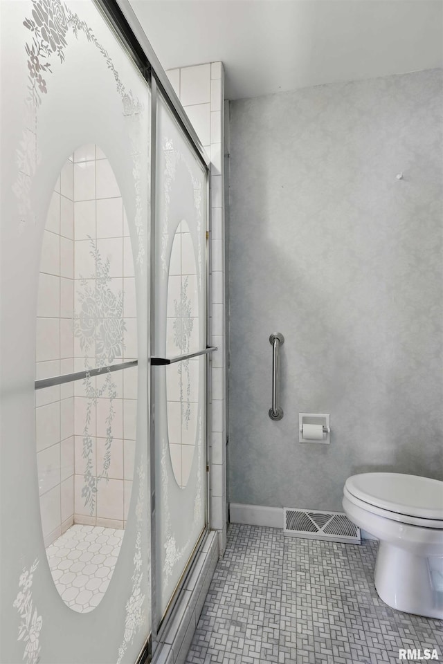 bathroom with toilet, visible vents, and a shower stall